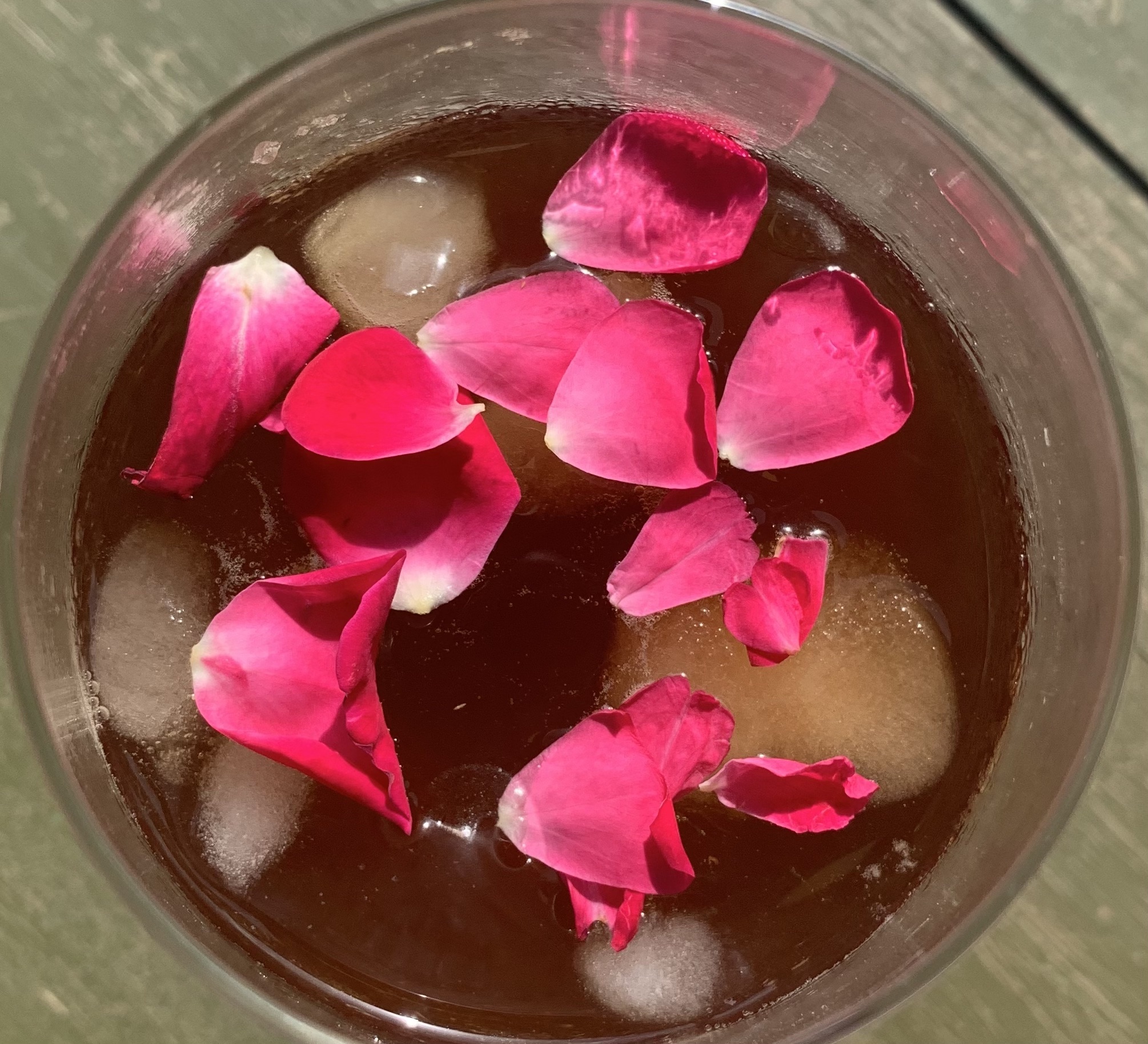 a glass with ice, coffee and pink rose petals